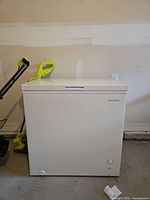 Front view of closed freezer showing brand badge, thermostat control, drain cap