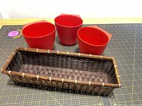Three red IKEA planters and brown wicker basket overall view