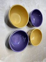 Top view of two yellow and two purple ceramic bowls