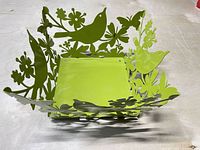 Overall view of green metal basket showing bird and floral cut-outs