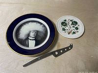 Two decorative plates and cheese knife on tabletop