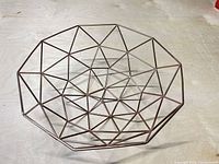 Oblique view of entire copper-tone geometric wire bowl