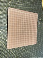 Closed brown plaid hardcover scrapbook on cutting mat