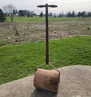 Full view standing upright showing wooden drum, metal frame, wooden T-handle
