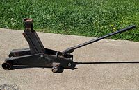 Side view of hydraulic floor jack showing overall structure and handle