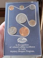 Front of acrylic award case showing coin arrangement and Gates logo