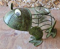 front side view of metal and glass frog tealight holder showing eyes, feet and body