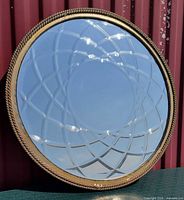 Front view of circular mirror showing etched pattern and gold frame