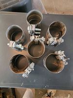 Top view of six stainless steel exhaust clamps showing overall condition and hardware