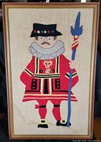 Front view of framed embroidery showing entire Beefeater design and frame