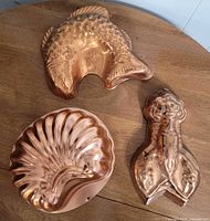 Fish, scallop shell and lobster copper molds on tabletop