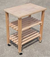 Full view of wooden rolling cart showing top, shelves, legs, and casters