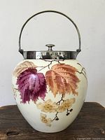 front view of biscuit barrel showing painted leaves and blossoms