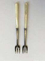 Two miniature sterling silver forks with mother of pearl handles displayed side by side