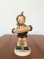 Front view of porcelain boy holding accordion