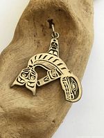 front view of engraved sterling silver killer whale pendant on driftwood