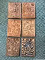 All six carved wood panels laid out on floor