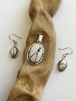 Full view of pendant and both earrings on driftwood background