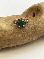 Top view of silver ring showing emerald centre and diamond halo