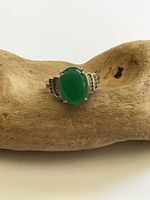 Top view of sterling silver ring with green oval cabochon and accent stones