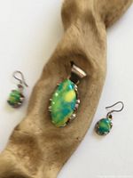 Pendant and earrings set displayed on driftwood support