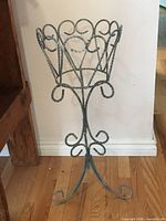 Full view of blue iron plant stand against wall