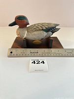 Full view of Green-winged Teal decoy on wood base with ruler for scale