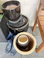 Stack of black and brown glazed planters with boots and beige planter