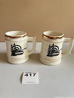 Front view two Hycroft steins showing curling graphic and gold rims