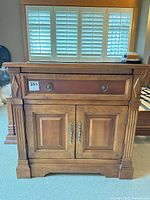 Front view of nightstand closed, shows two-tone finish and decorative hardware
