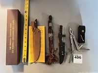 Entire lot lined up: Grohmann box, sheath, leaflet, carved stick, multi-tool with sheath, black pouch