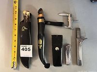 Group shot showing all knives, tools and sheaths with measuring tape