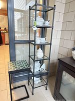 Etagere with six glass shelves beside C-shape side table