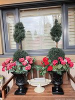 Pair of black urn planters with artificial topiary and flowers, ceramic pedestal planter positioned in front