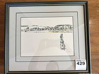 Full view of framed artwork showing cityscape, woman with bicycle, matting and frame