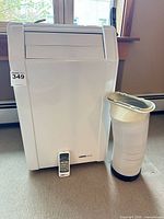 Front view of air conditioner with remote and hose