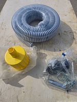 Coiled hose, yellow strainer, bagged fittings on tabletop