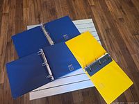 Binders opened flat showing metal ring mechanisms and inside covers