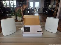 Two Orbi units flanking box containing Grandstream ATA