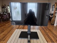 Front view of 32" RCA LED TV on stand with remote visible