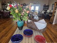 Overall view of plates, basket, Blue Mountain Pottery vase with silk flowers