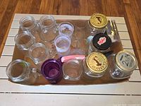 Top view of assorted glass jars, shot glasses, purple mug, mini skillet, ceramic shakers in cardboard tray