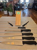 Six knives laid out beside wooden block