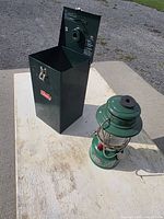 Lantern beside closed green metal Coleman case