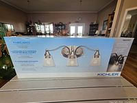 Front of sealed box showing image of three-light vanity fixture