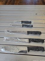 Five knives in plastic sleeves laid out