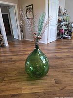 Front view of green glass demijohn bottle on floor