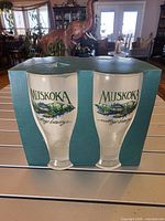 Front view of two glasses in cardboard holder showing Muskoka logo