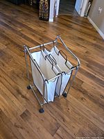 Front angle showing chrome frame, caster wheels and two white bags