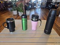 Four travel drinkware items standing upright